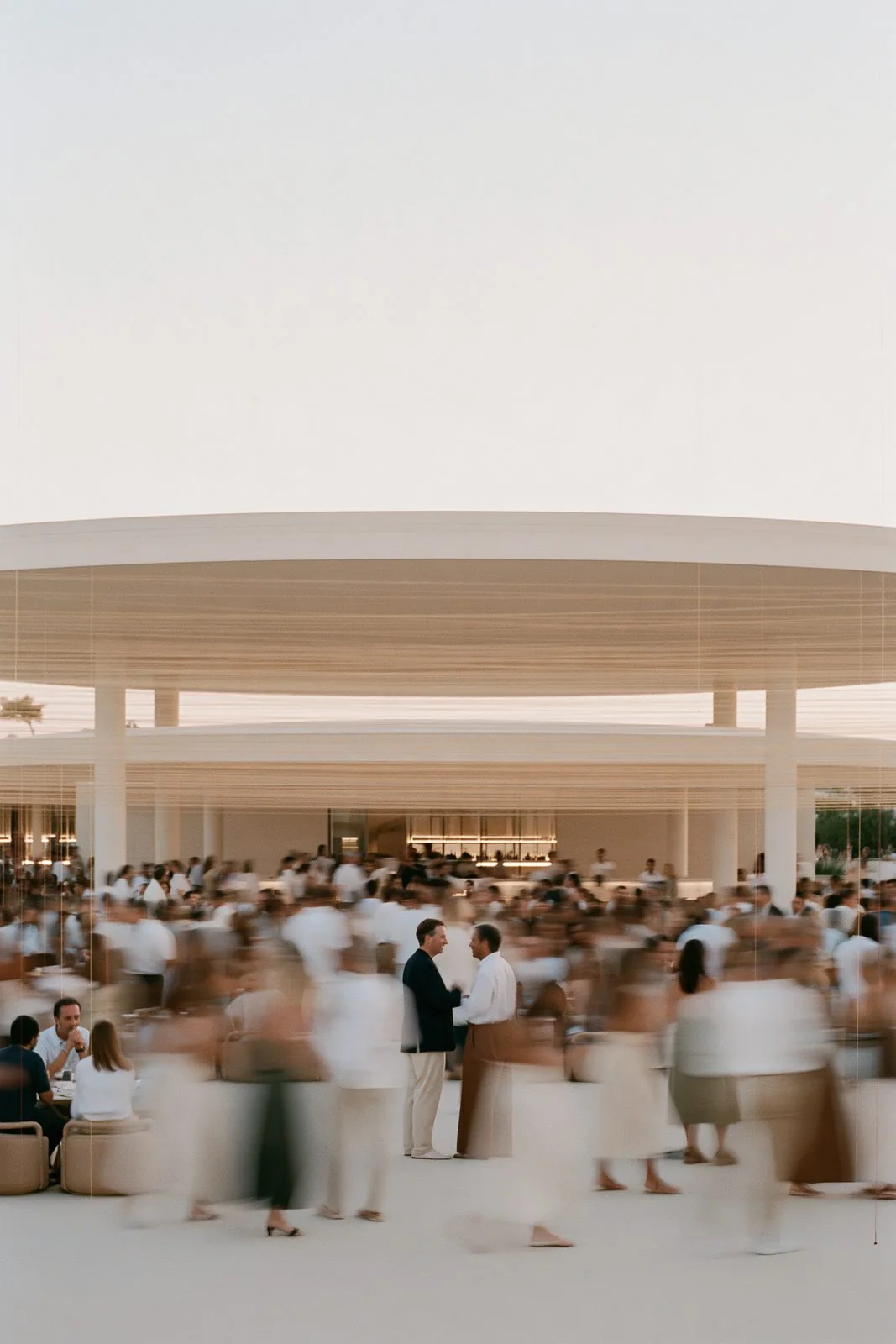 Guests in white beneath a pale pavilion at dusk